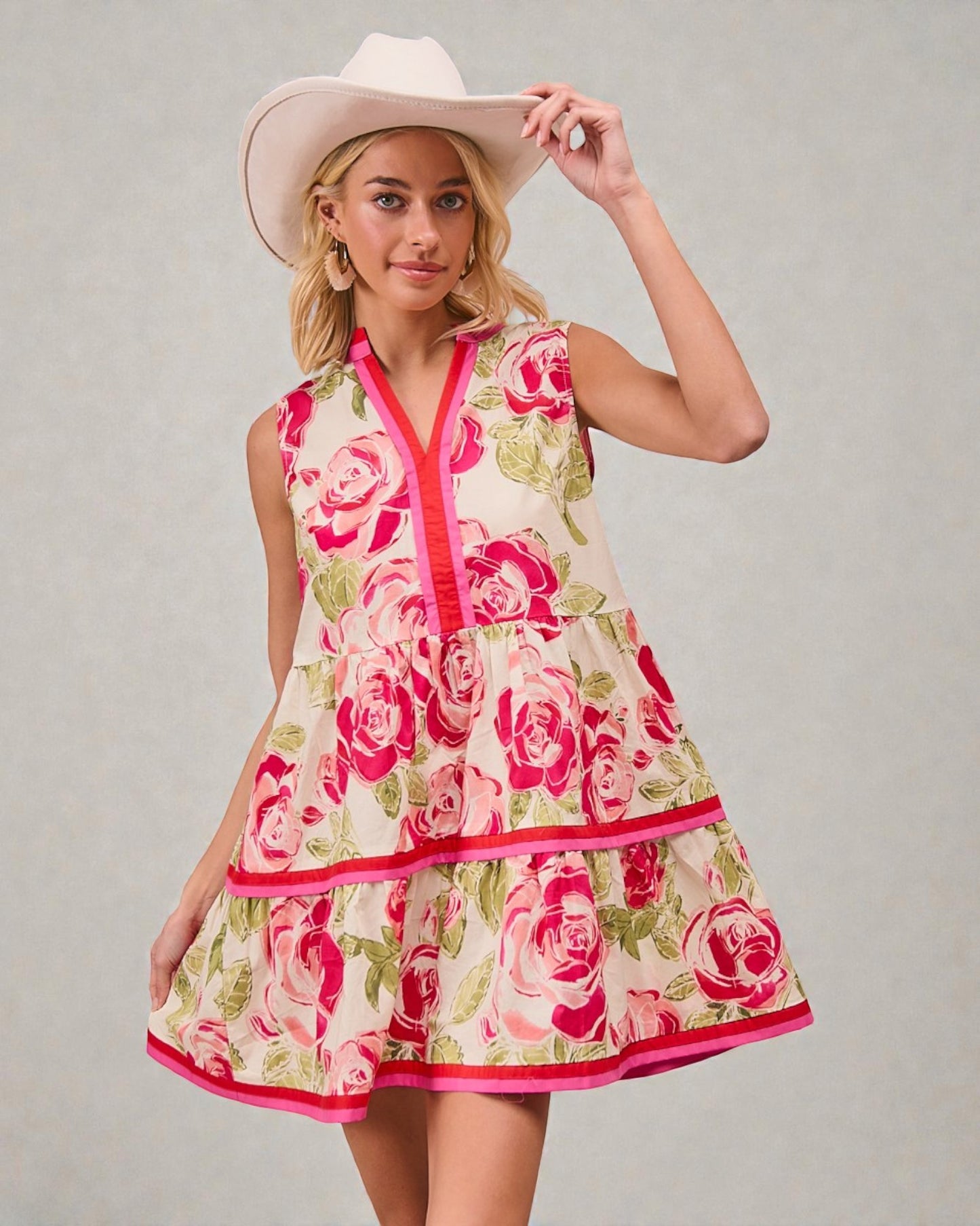 Woman wearing a floral dress and cowboy hat against a plain background