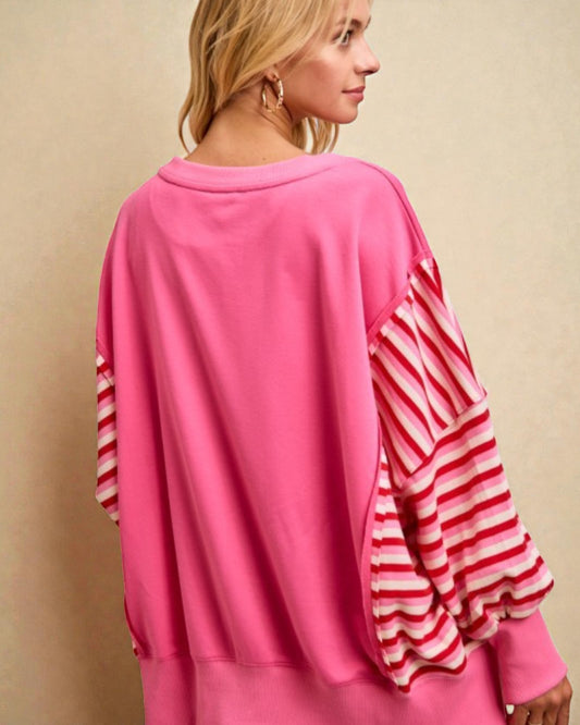 Woman wearing a pink outfit with red and white striped sleeves against a beige background