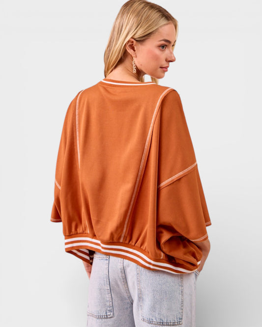 Person wearing a brown oversized sweater with white stripes on a light gray background