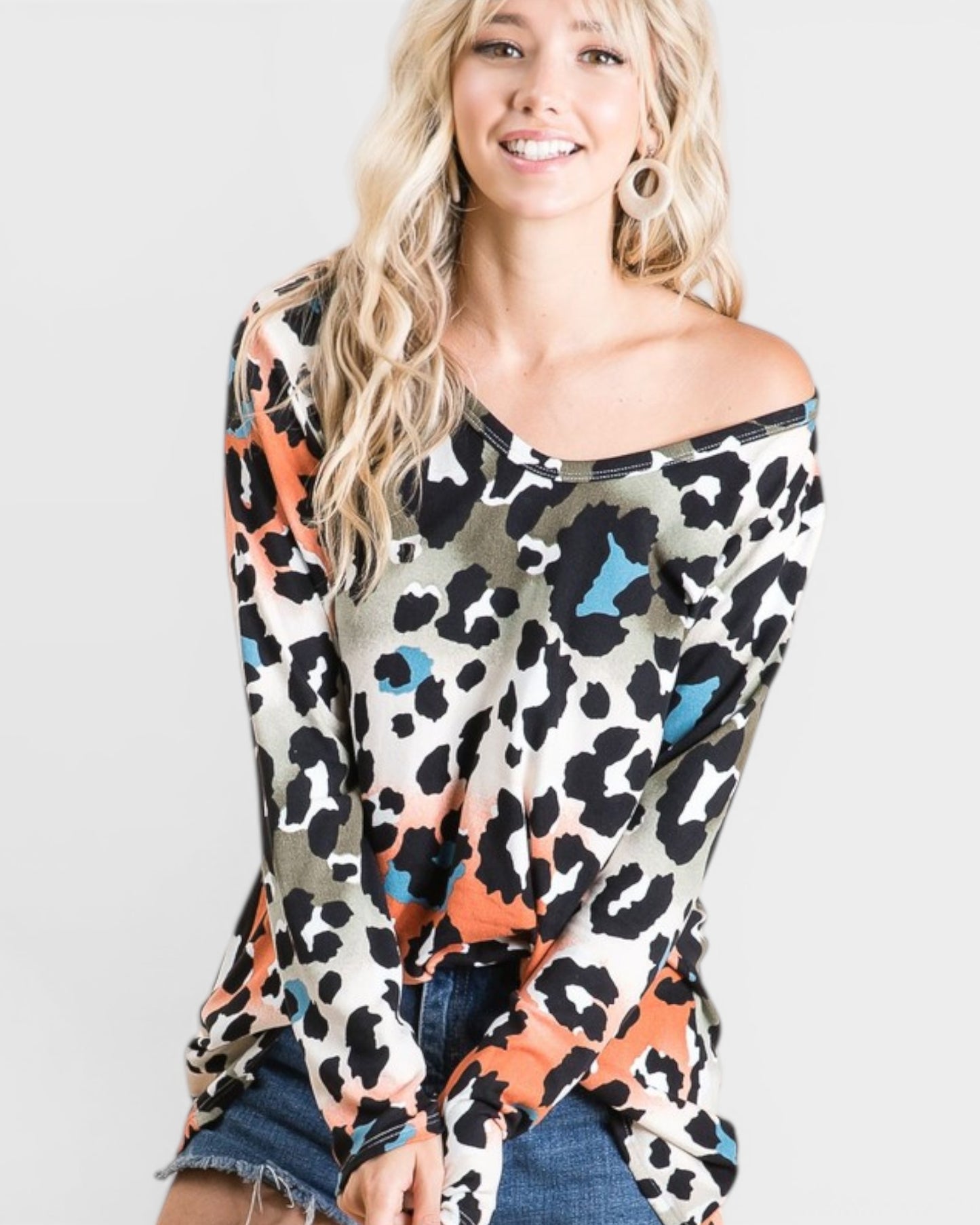 Woman wearing a colorful leopard print off-shoulder top on a light gray background