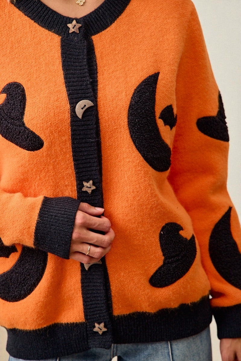 Orange cardigan with black heart patterns worn by a person.