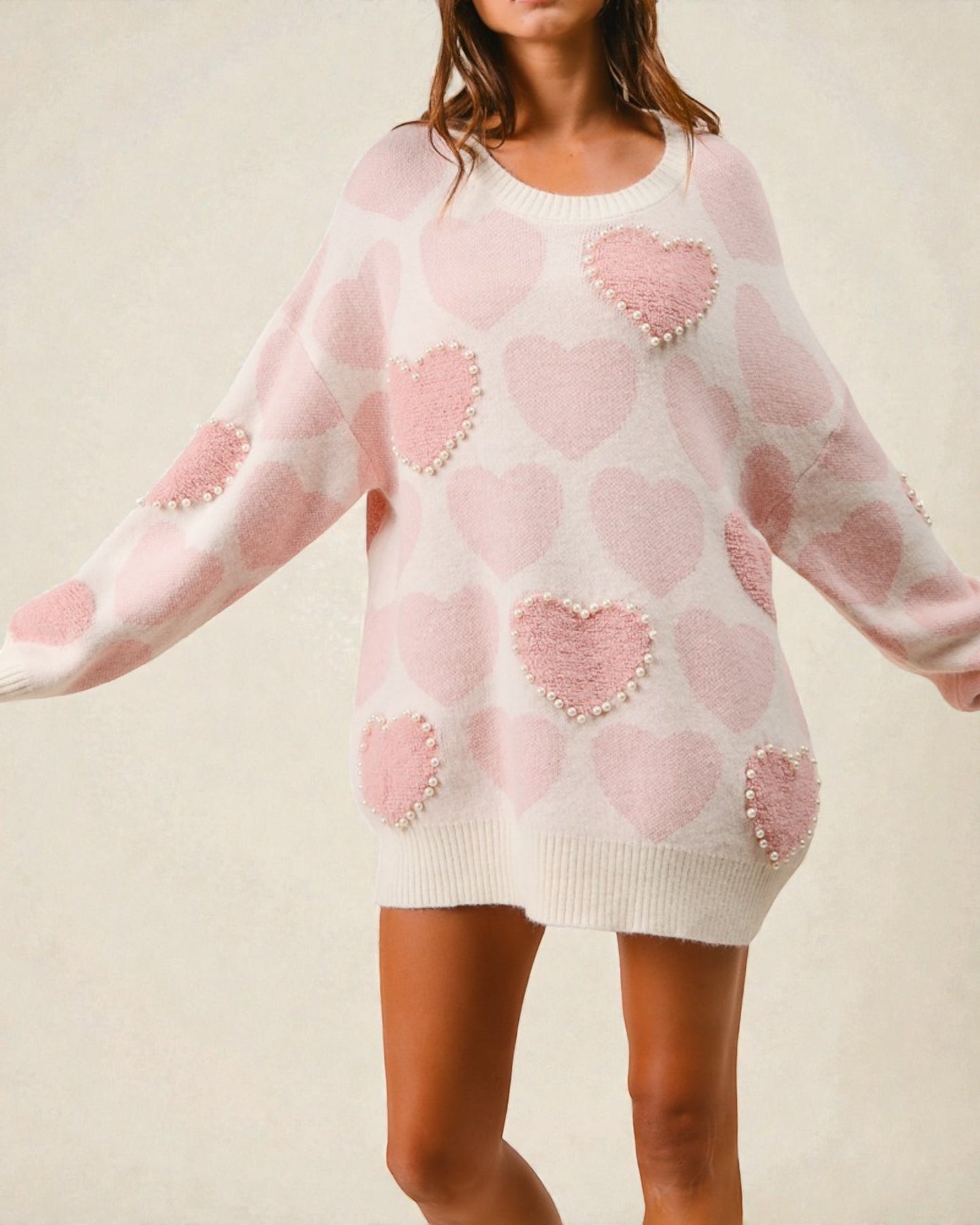 Pink sweater dress with heart patterns on a neutral background