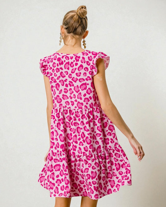 Woman wearing a pink leopard print dress against a plain background