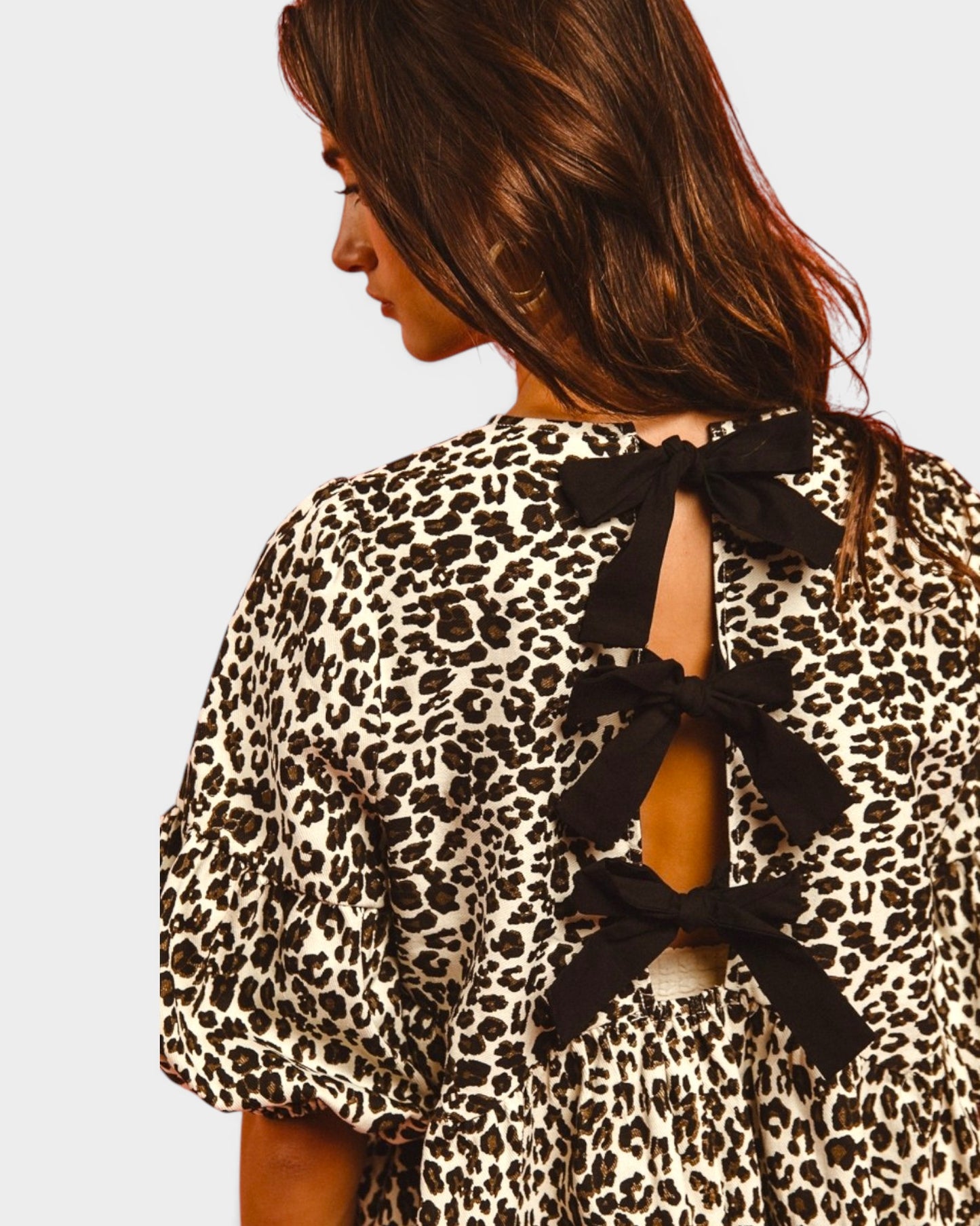 Leopard print top with black bow details on a plain background