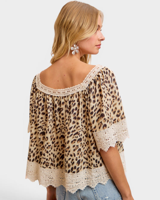 Woman wearing a leopard print top with lace details on a white background