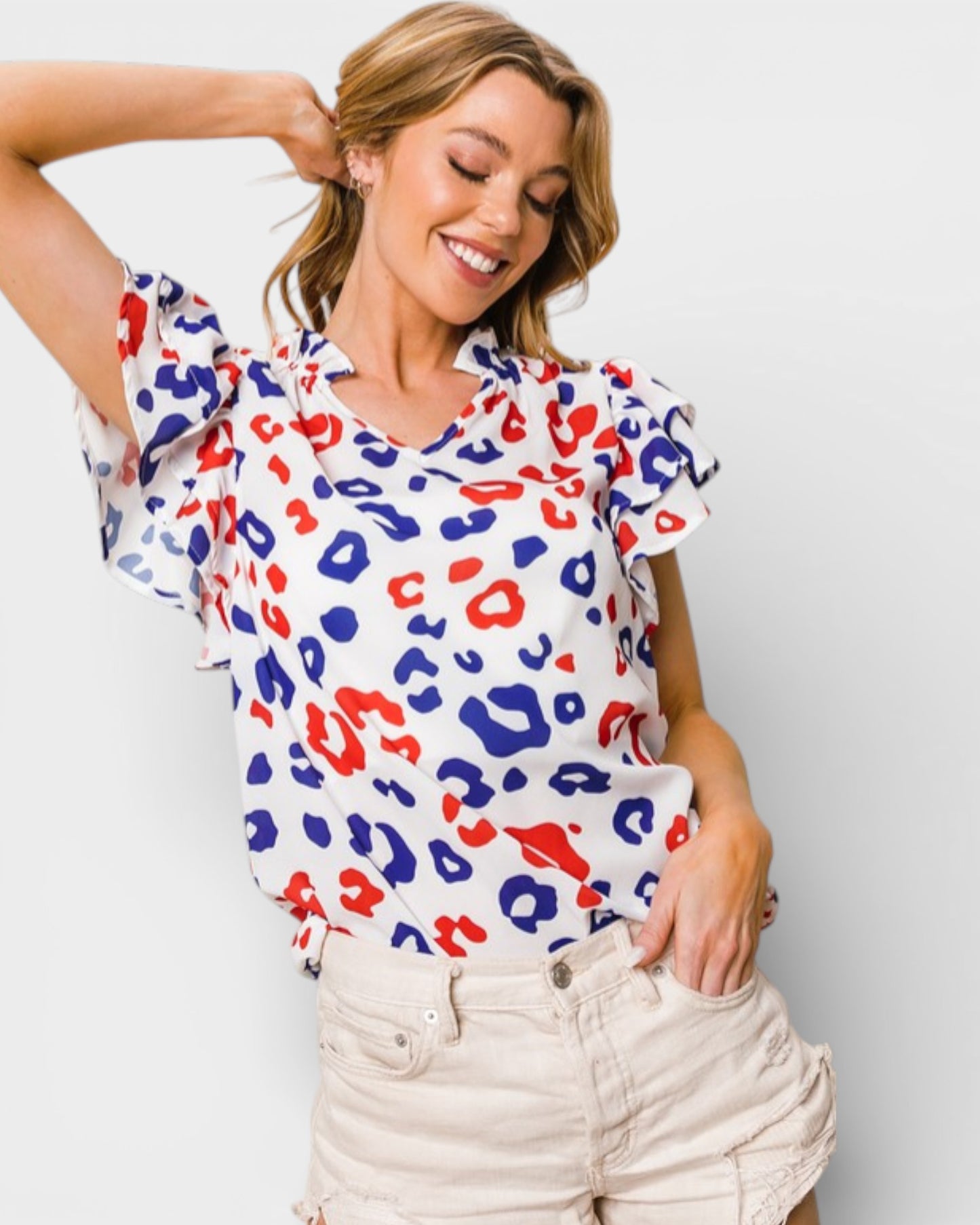 Woman wearing a colorful leopard print top against a plain background