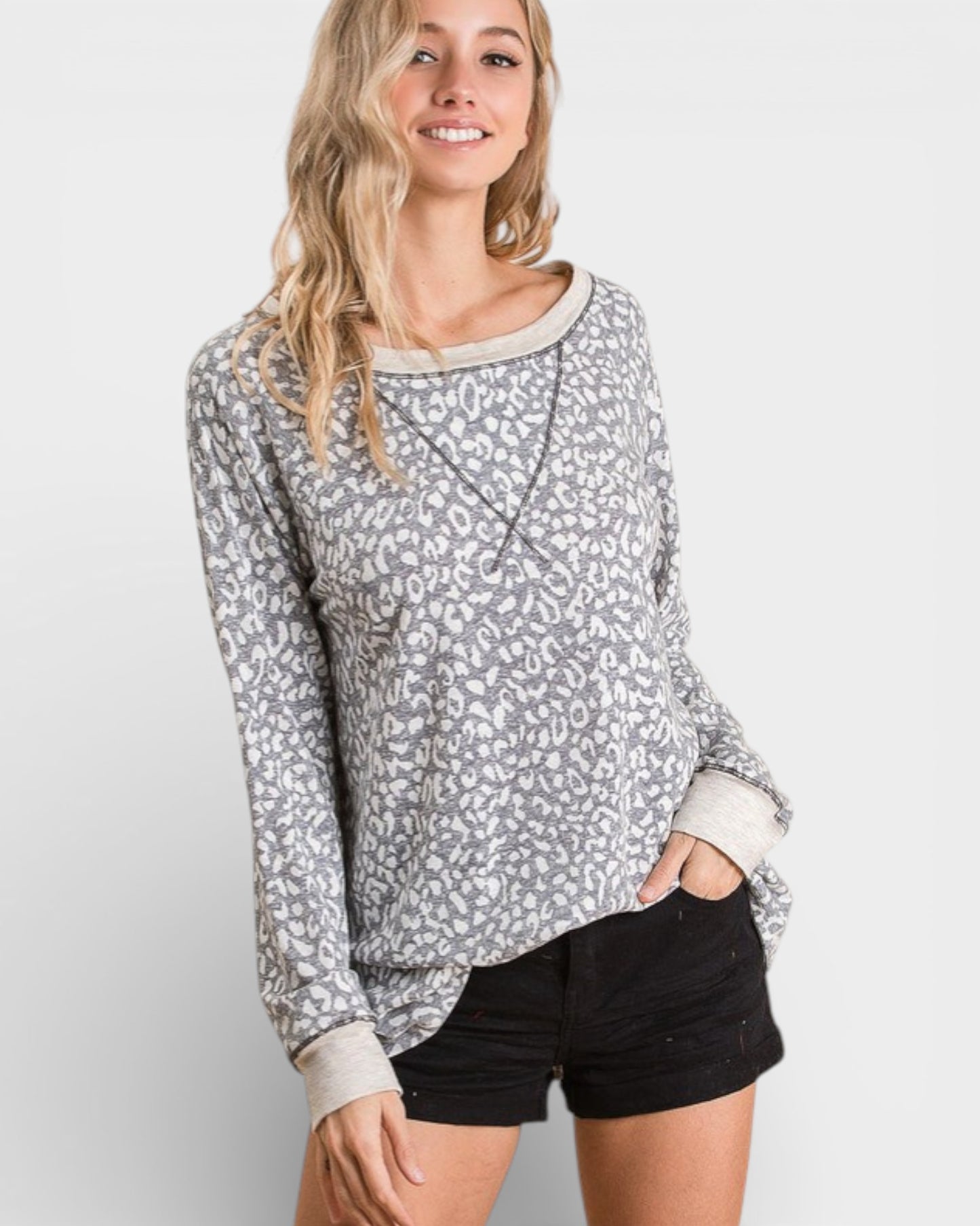 Woman wearing a gray patterned long-sleeve shirt and black shorts on a white background