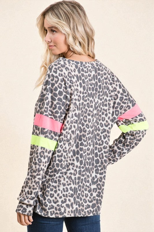 Woman wearing a leopard print top with colorful sleeves on a beige background