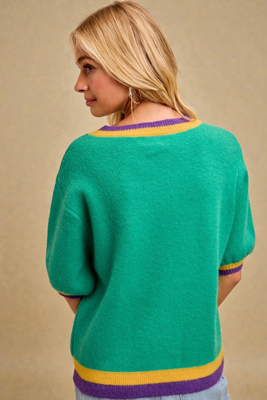 Woman wearing a green sweater with purple and yellow accents on a beige background