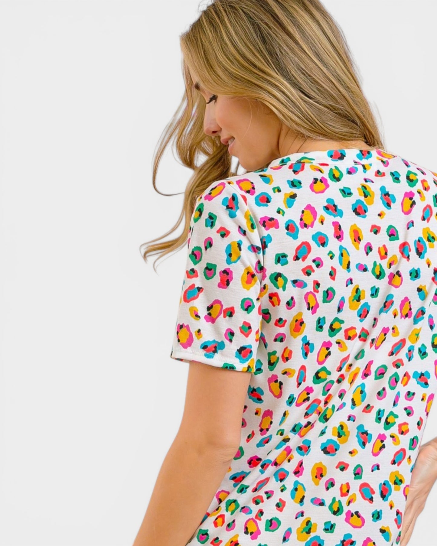Woman wearing a colorful leopard print top on a white background