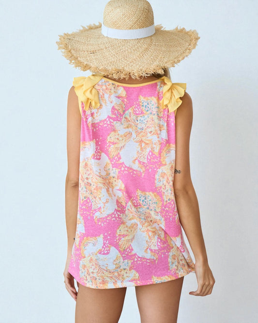 Person wearing a pink floral dress with yellow ruffled sleeves and a wide-brimmed straw hat on a light blue background