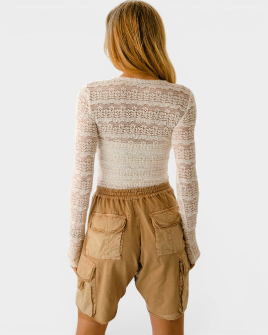 Person wearing a patterned long-sleeve top and beige cargo shorts on a white background