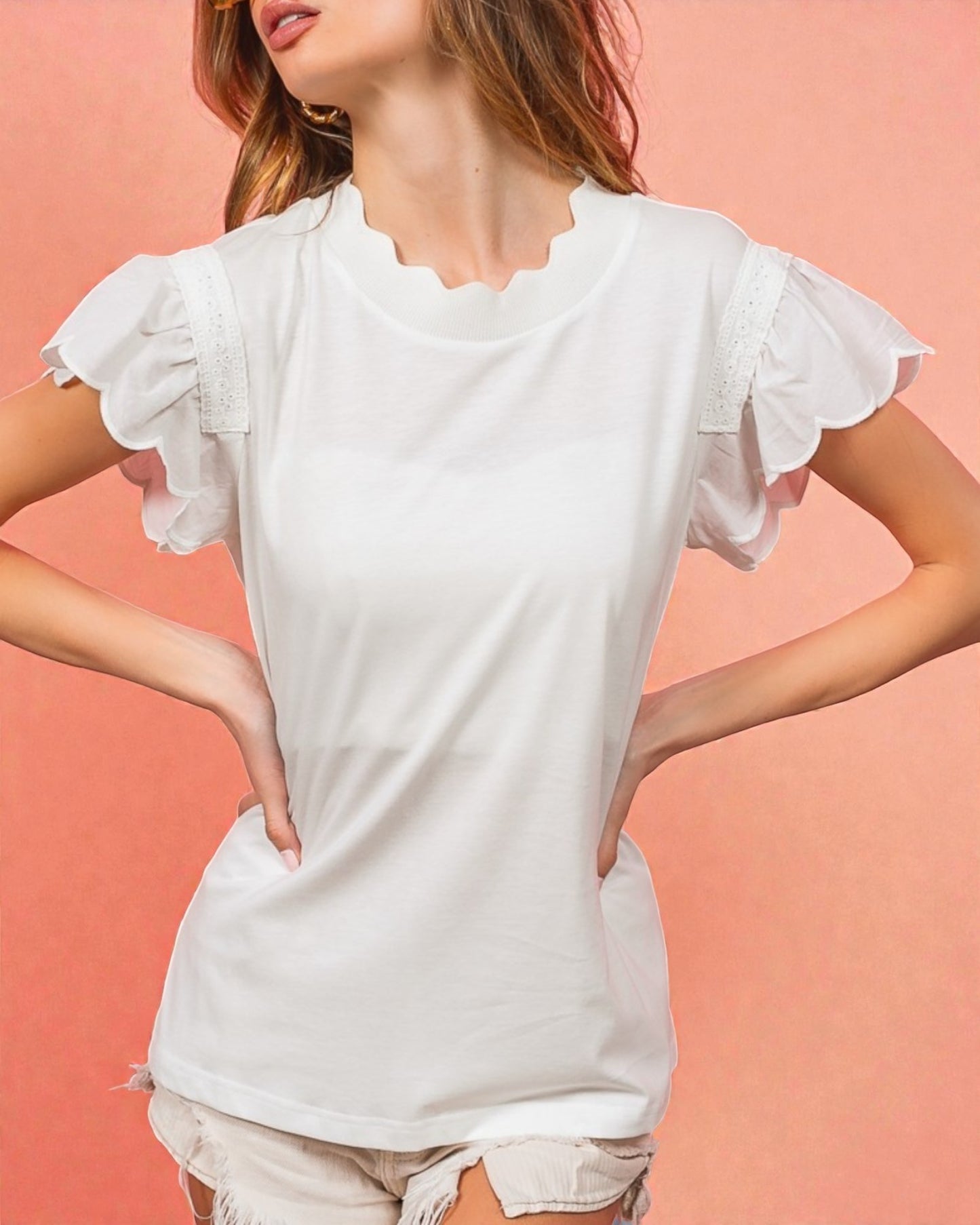 Woman wearing a white blouse with ruffled sleeves against a pink background