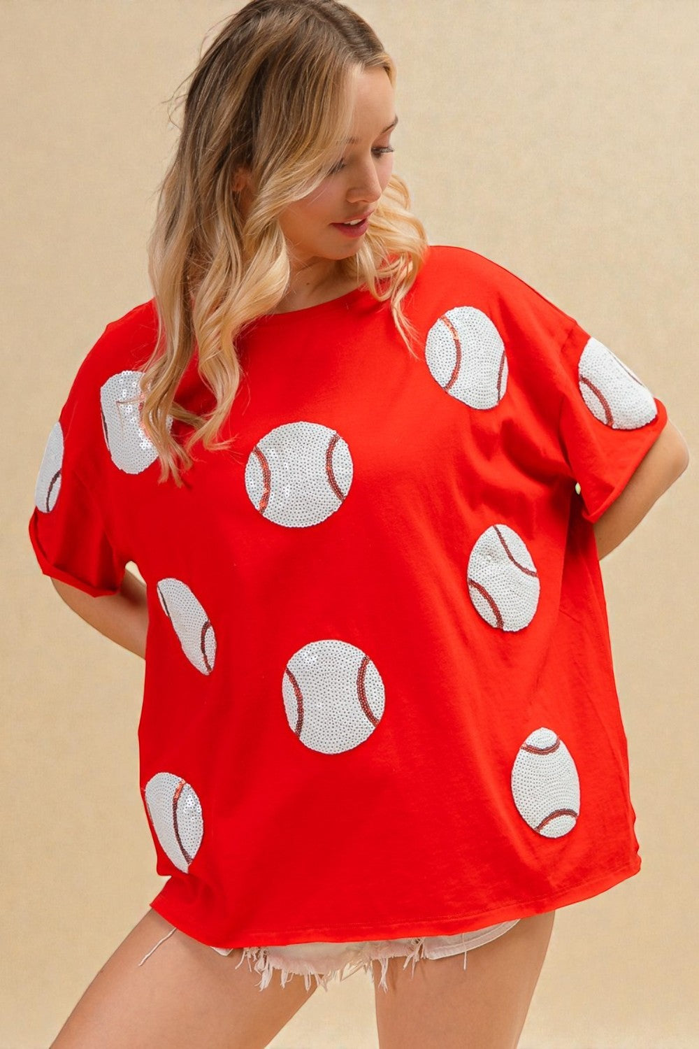 Woman wearing a red shirt with white baseball patterns on a beige background