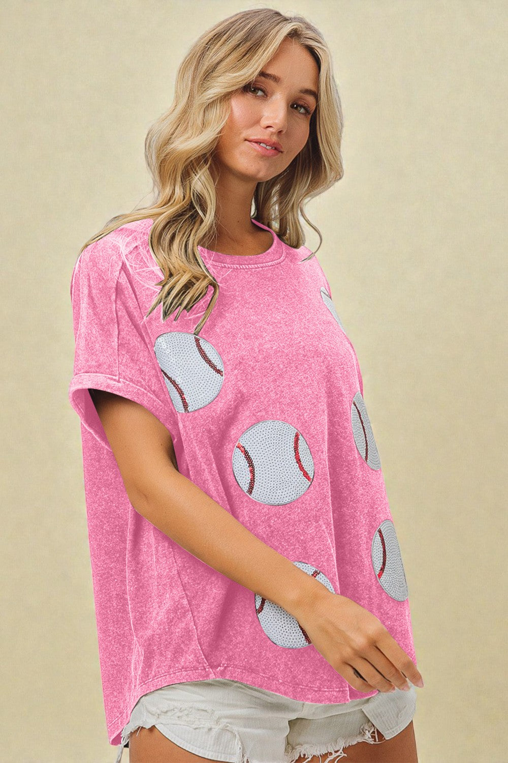 Woman wearing a pink t-shirt with baseball graphics on a beige background