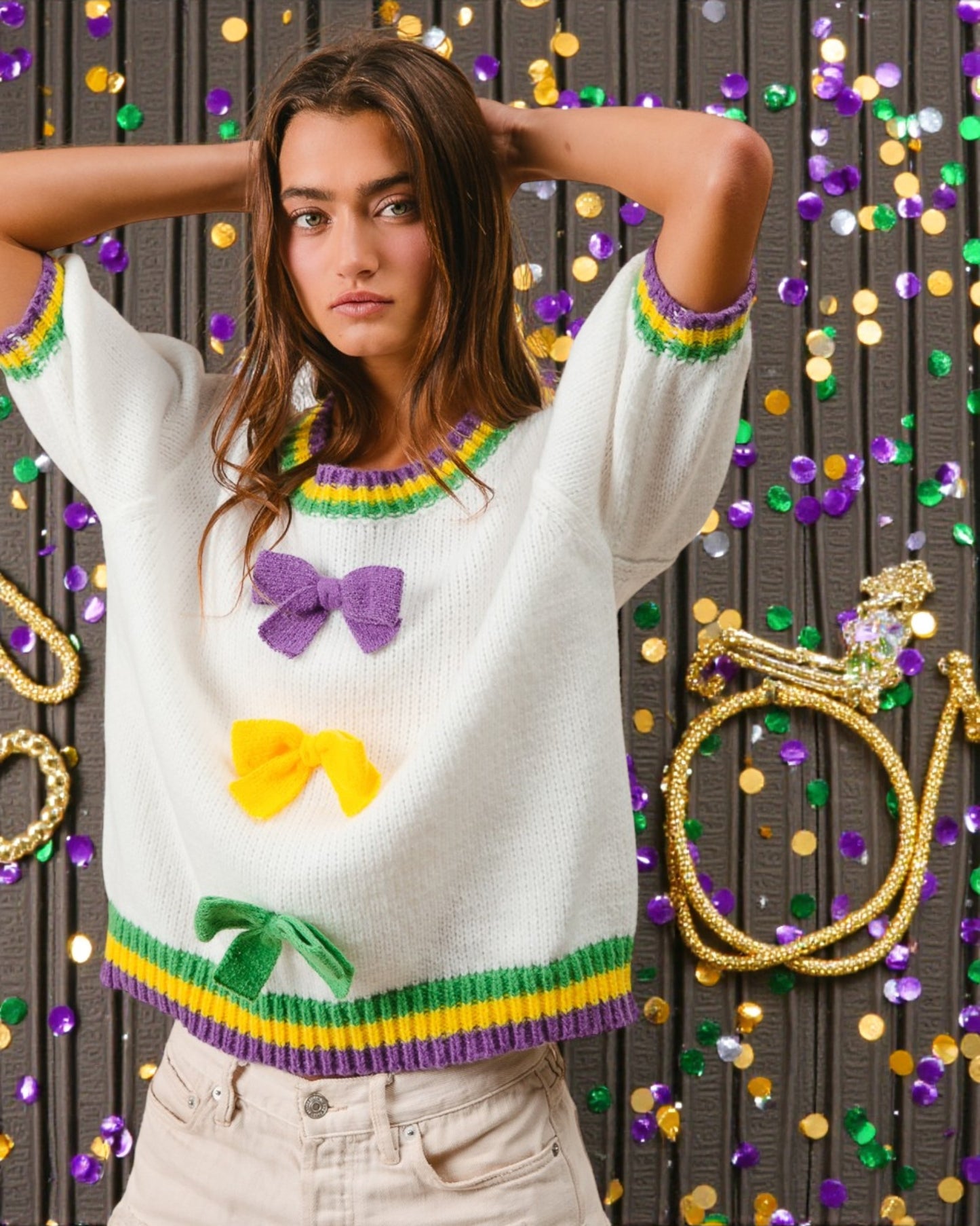 Woman wearing a white sweater with colorful bow patterns against a festive background.