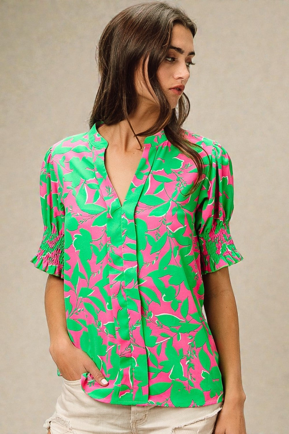 Woman wearing a pink and green patterned blouse against a beige background