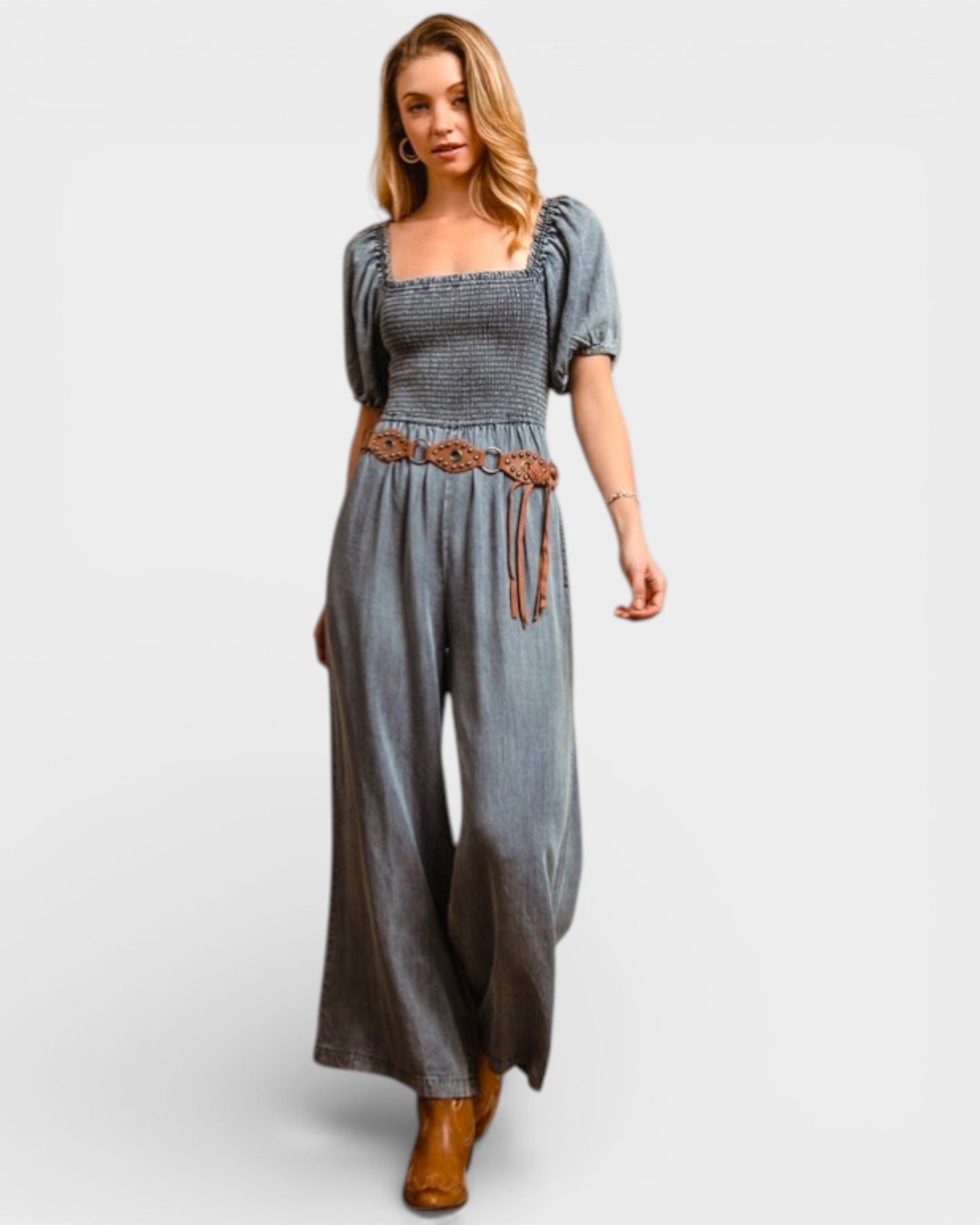 Woman wearing a gray jumpsuit with a belt on a light gray background