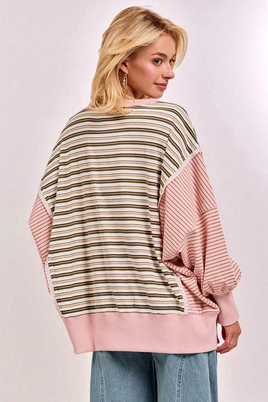 Woman wearing a striped sweater with pink sleeves and trim on a white background