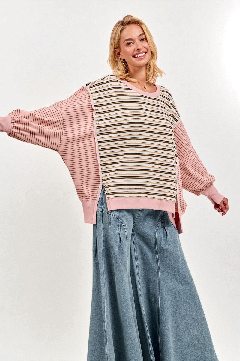 Woman wearing a striped sweater with pink sleeves and blue jeans on a white background