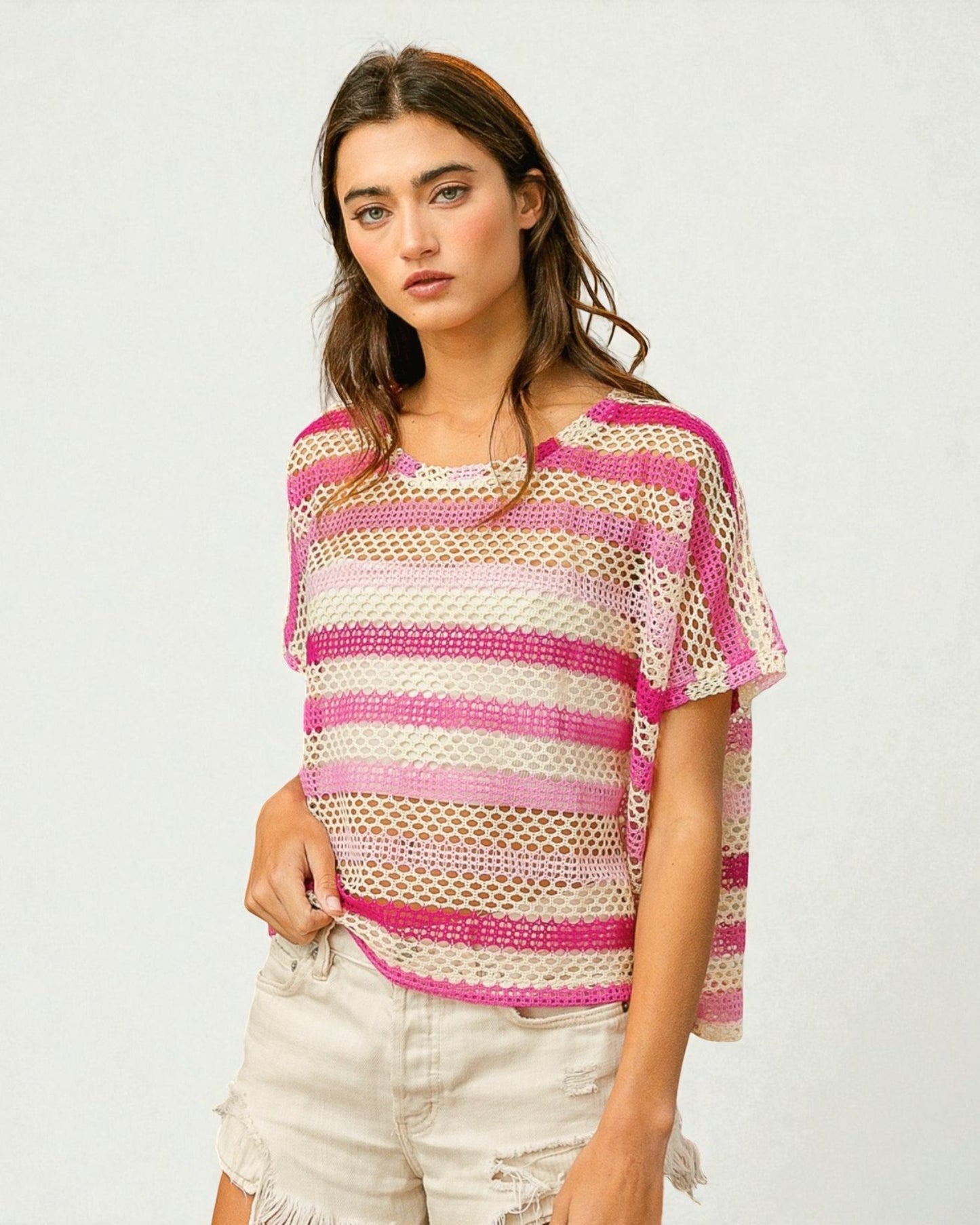 Woman wearing a pink and beige striped crochet top on a white background