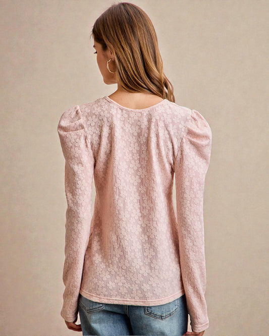 Woman wearing a light pink blouse with long sleeves on a beige background