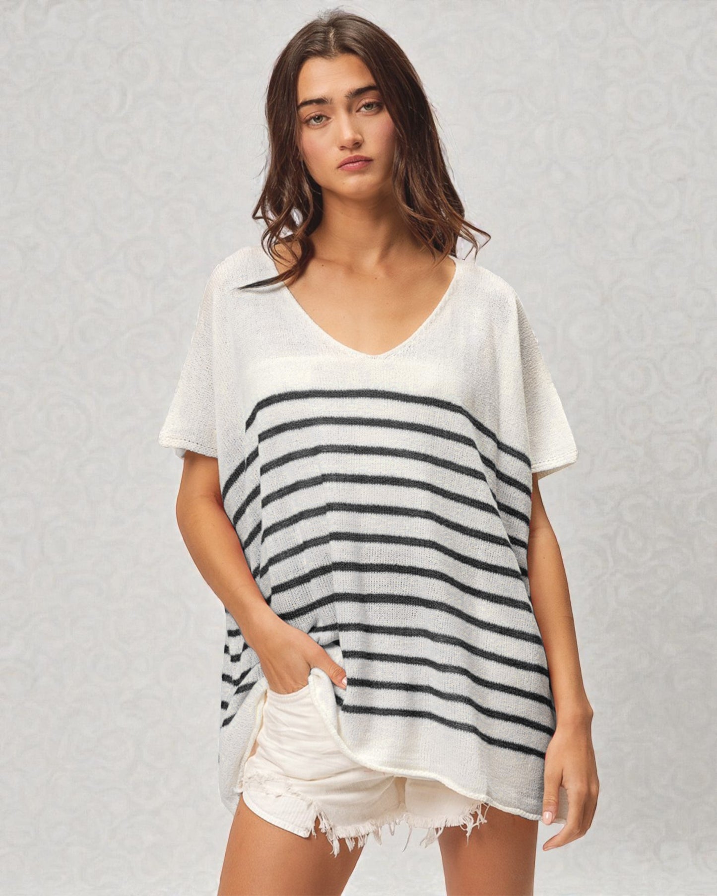 Woman wearing a white and navy striped t-shirt with white shorts on a light gray background