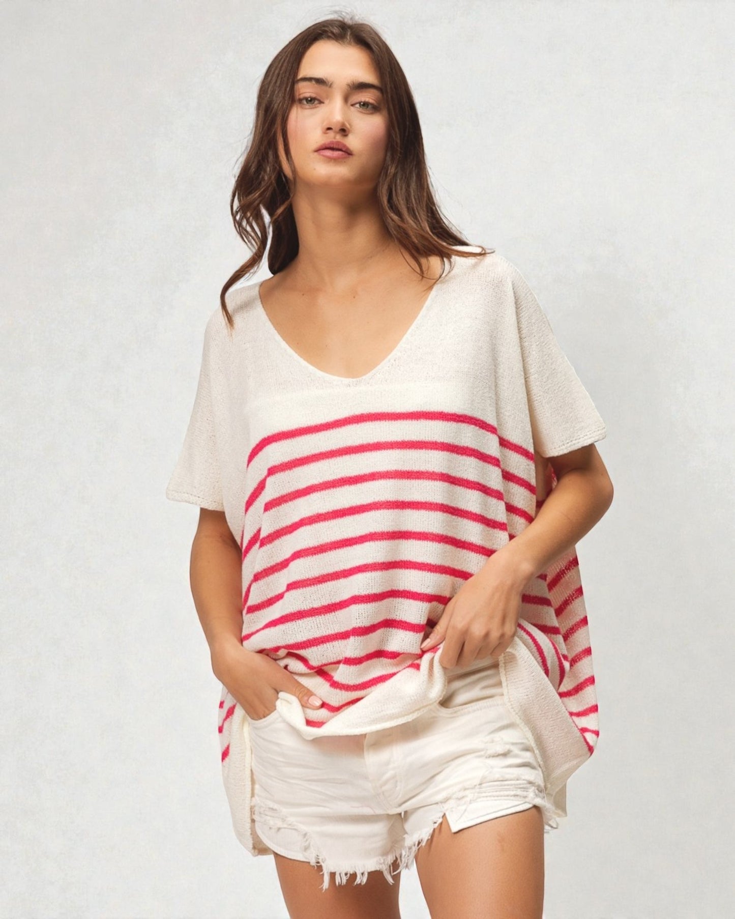 Woman wearing a white and red striped top with white shorts on a plain background