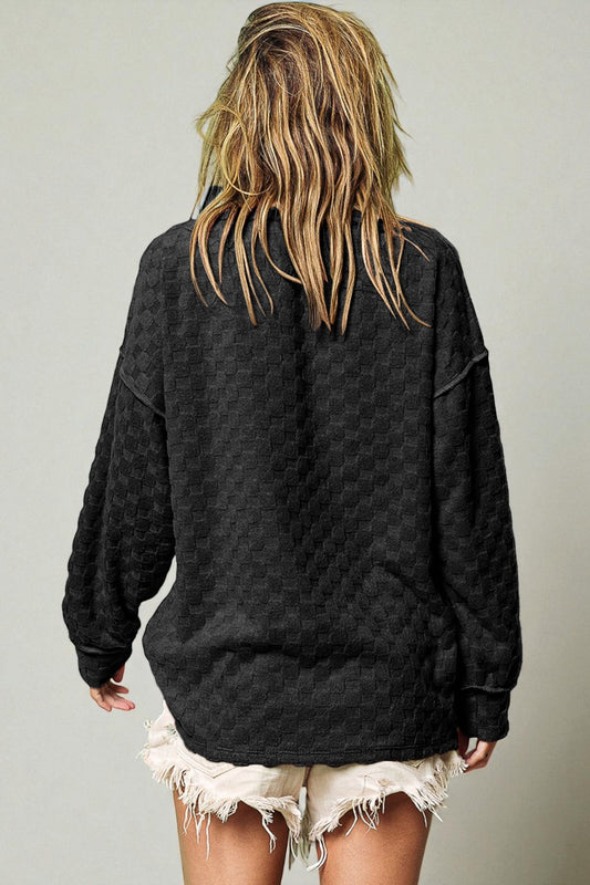 Person wearing a black quilted jacket with a plain background