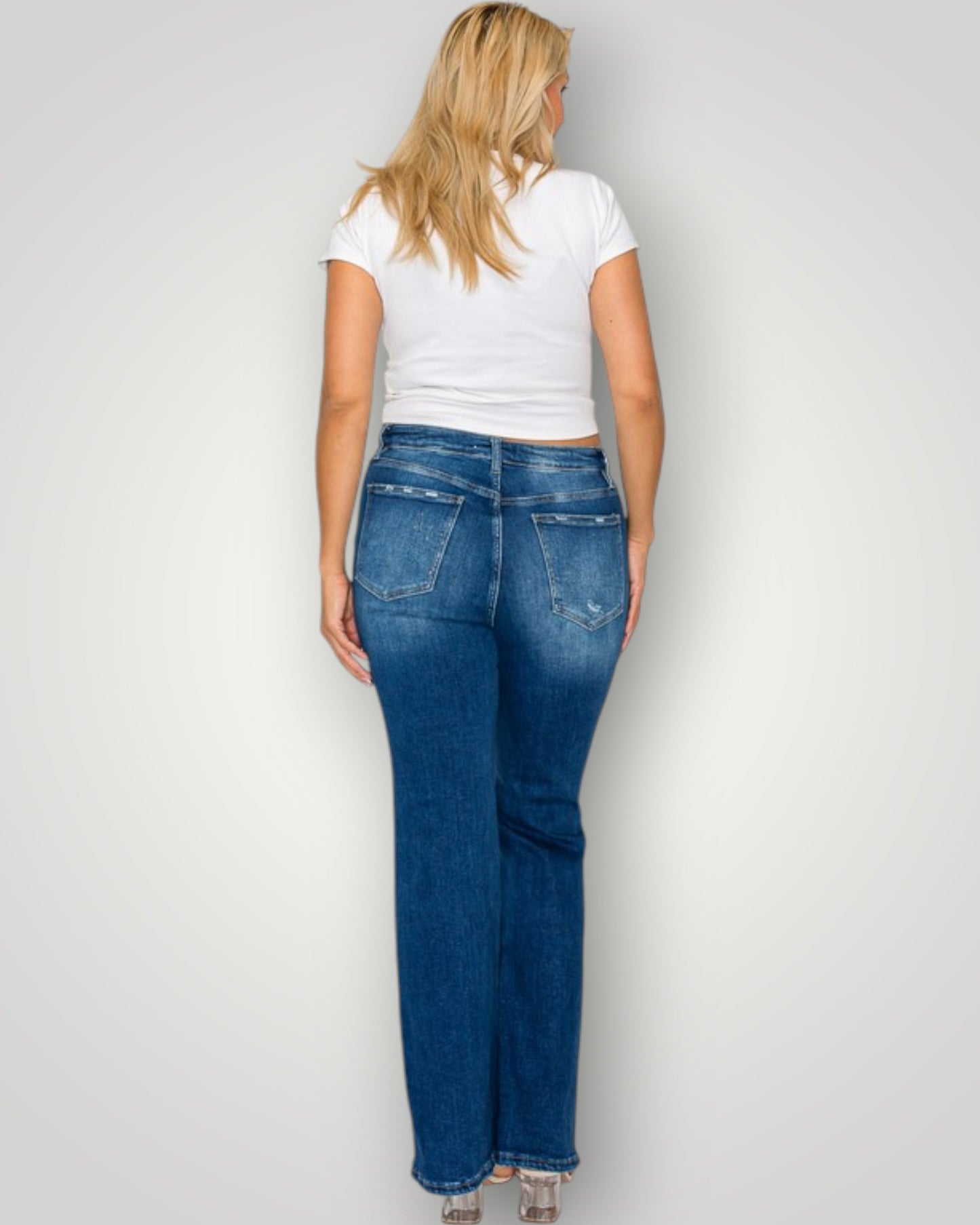Woman wearing blue jeans and a white t-shirt on a plain background
