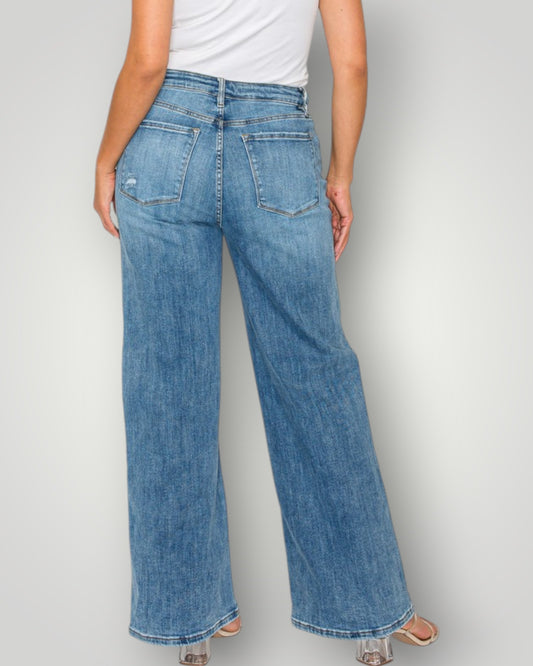 Person wearing blue jeans and a white top on a plain background