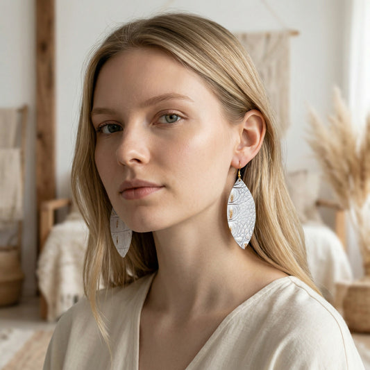 Woman wearing large, round earrings in a softly lit room.