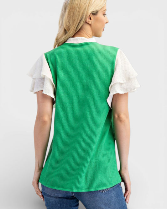 Woman wearing a green ribbed sweater over a white shirt on a light gray background