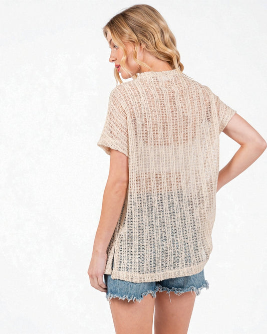 Woman wearing a beige textured top and denim shorts on a white background