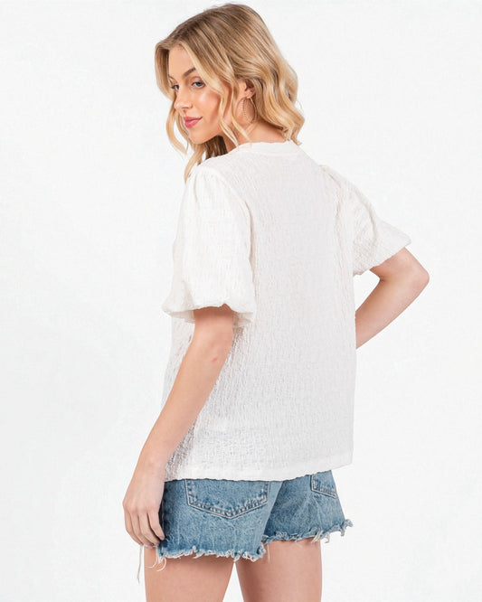 Woman wearing a white lace top and denim shorts on a white background