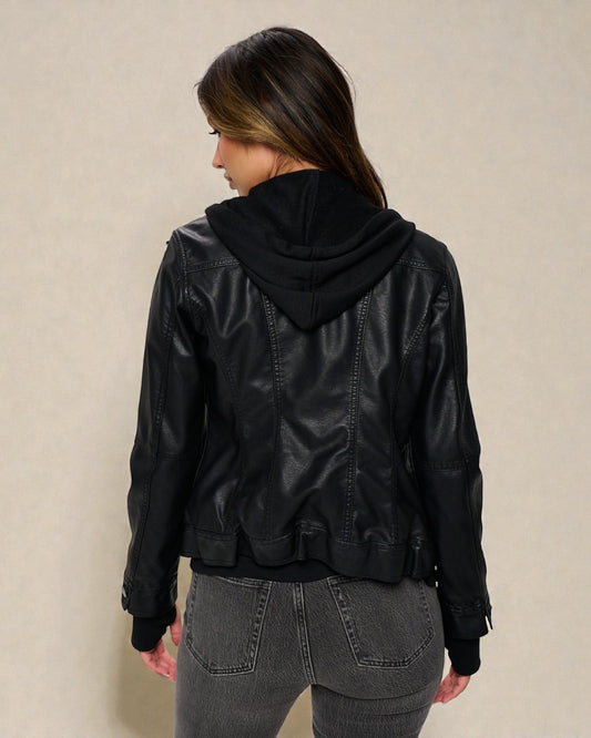 Person wearing a black leather jacket with a hood on a beige background