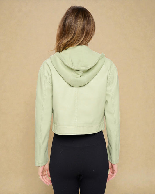 Person wearing a light green hoodie and black leggings against a beige background