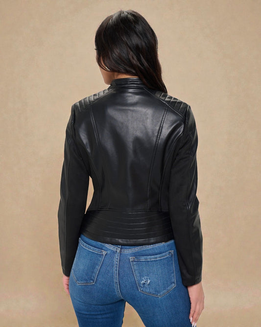 Person wearing a black leather jacket and blue jeans on a beige background