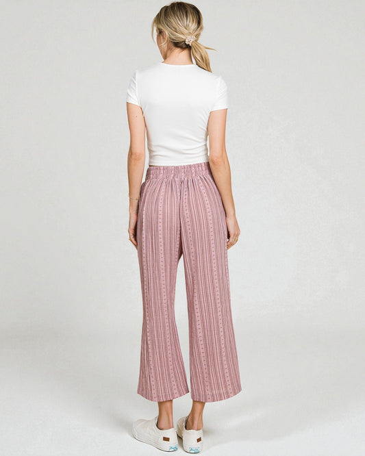 Woman wearing pink checkered pants and a white top on a plain background