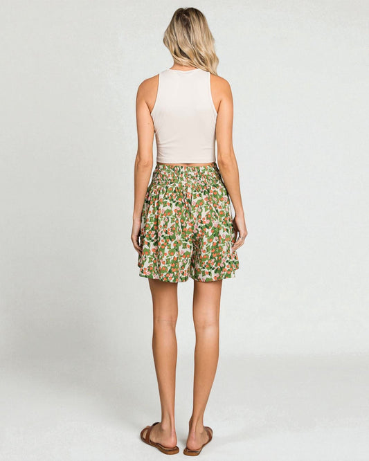 Woman wearing a floral skirt and white top on a plain background