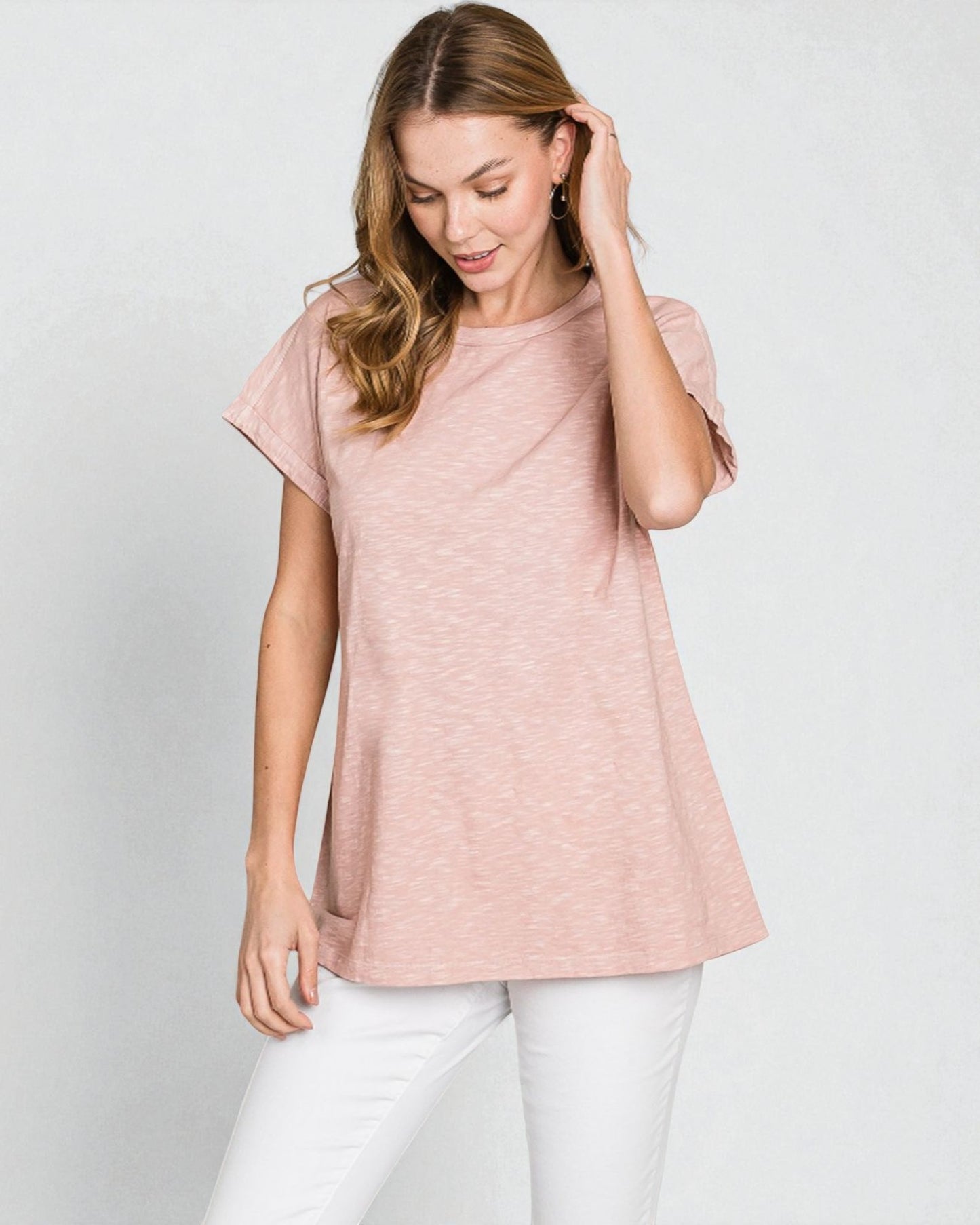 Woman wearing a pink t-shirt and white pants on a light gray background