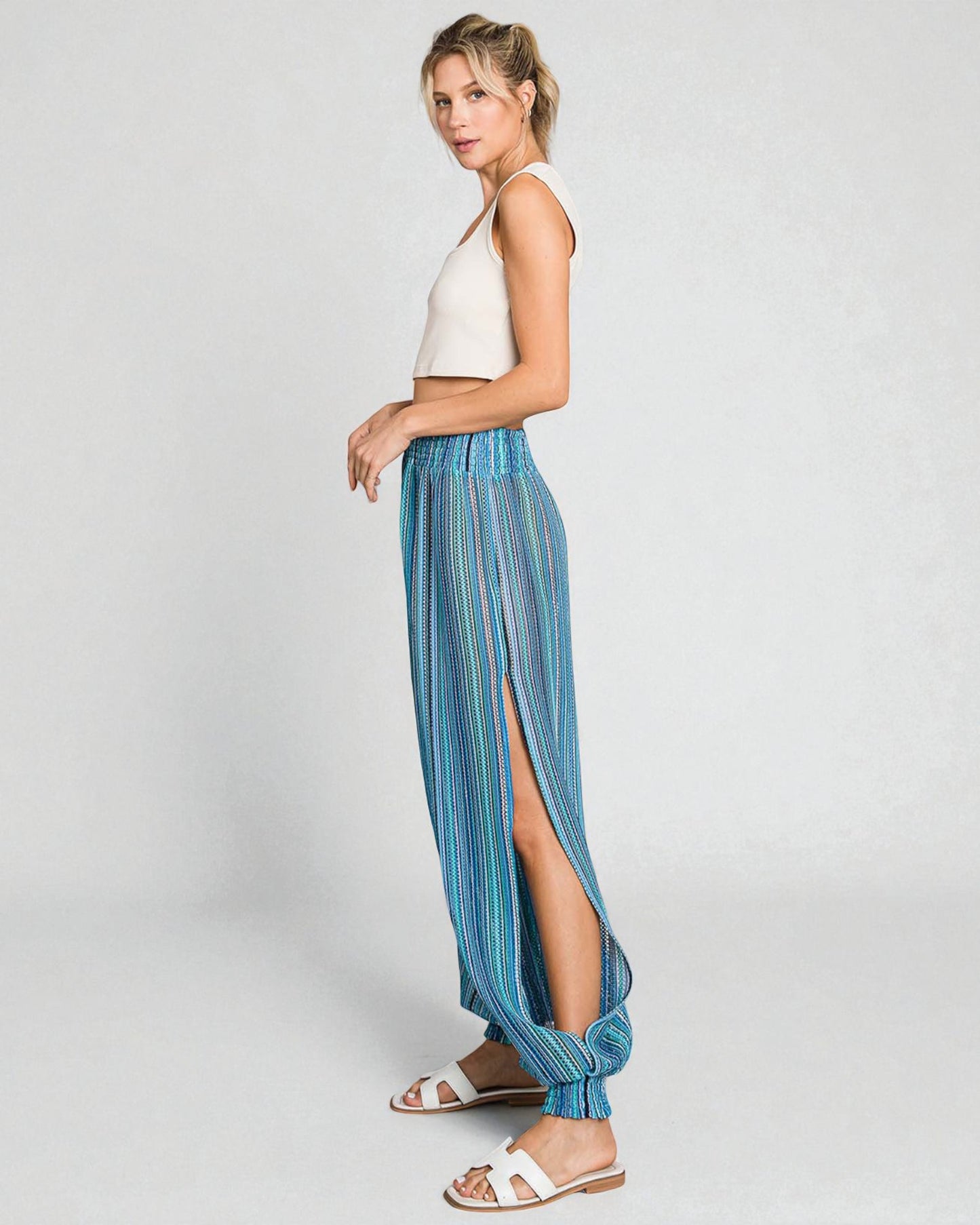 Woman wearing a white top and blue striped pants on a light gray background