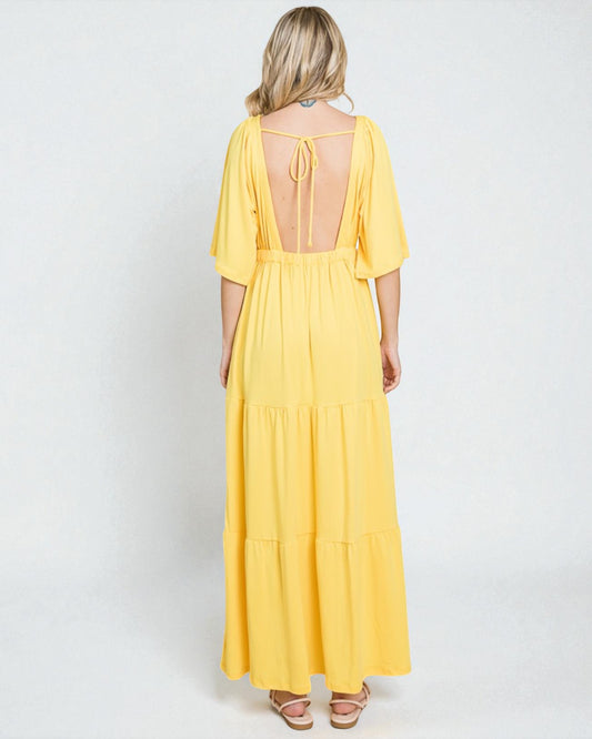 Woman wearing a yellow dress with a backless design on a white background