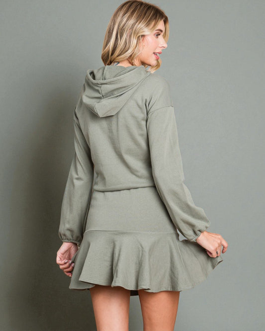 Woman wearing a green hoodie and skirt set against a gray background