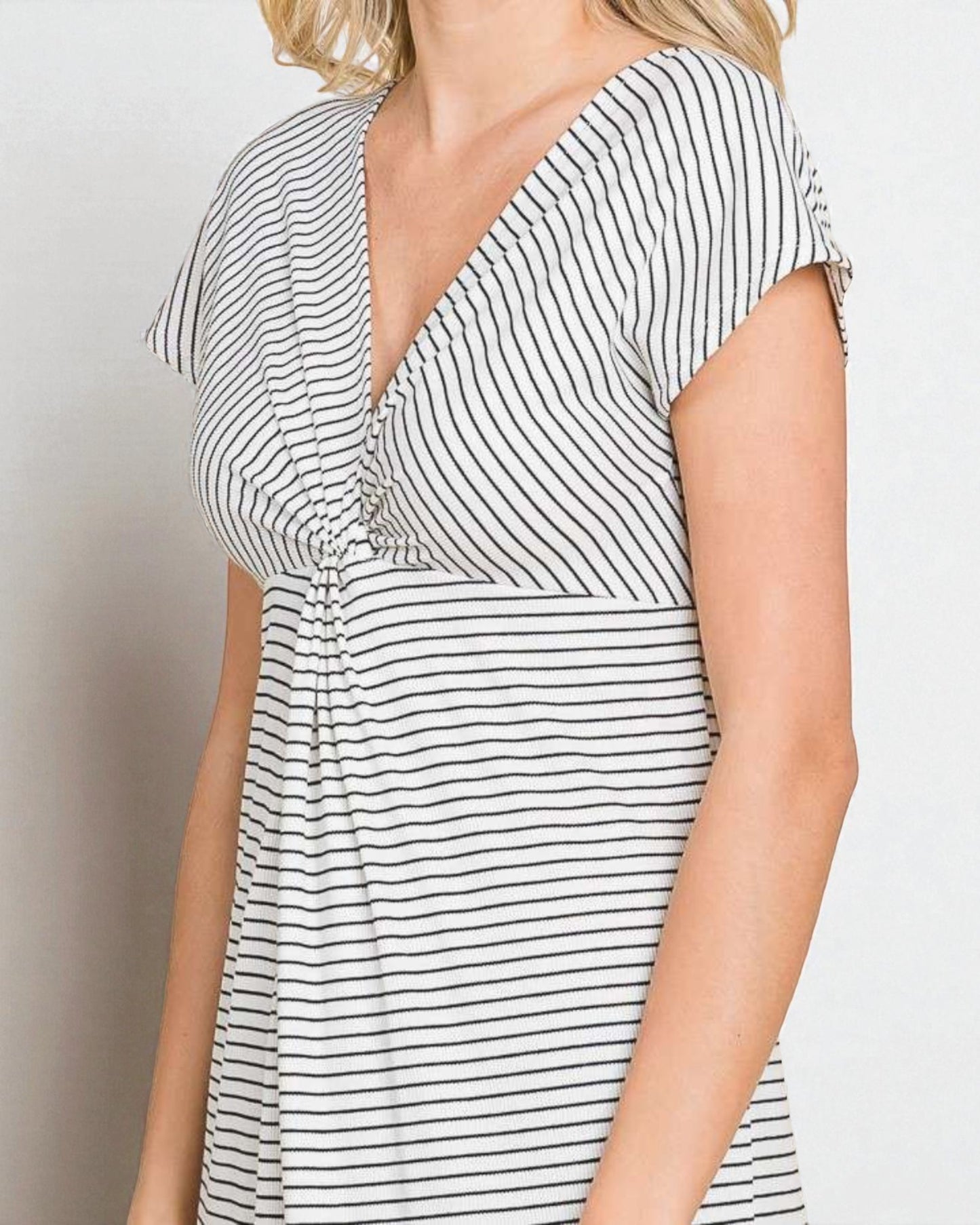 Woman wearing a black and white striped dress against a plain background