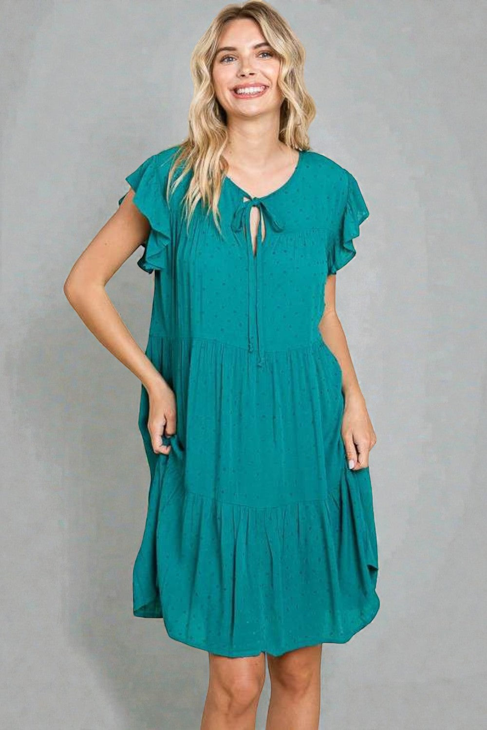 Woman wearing a teal dress against a gray background