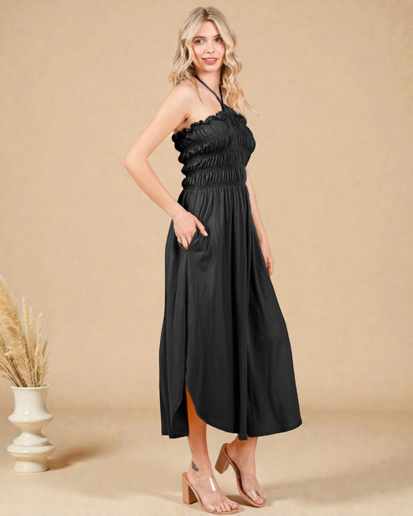 Woman wearing a black halter neck dress on a beige background