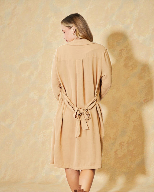 Woman wearing a beige dress against a textured beige background