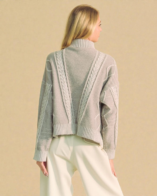 Woman wearing a gray sweater with intricate back design on a beige background