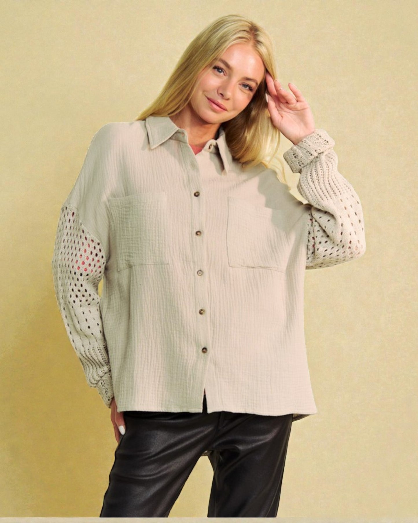 Woman wearing a light green button-up shirt with sheer sleeves against a beige background